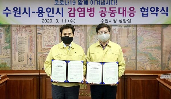 백군기 용인시장(왼쪽)과 염태영 수원시장이 11일 수원시청 상황실에서 코로나19 사태에 공동 대응하기 위한 업무 협약을 체결하고 기념촬영을 하고 있다. (사진제공=용인시청)
