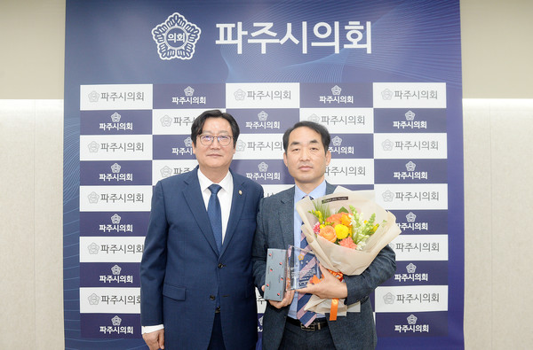 손배찬 의장(왼쪽)이 최유각 자치행정위원장에게 상패와 꽃다발을 전달한 뒤, 기념촬영 모습. (사진제공=파주시의회)