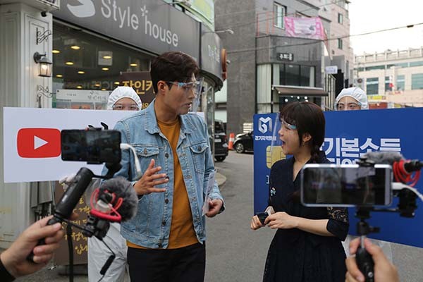 경기도 홍보대사 김일중 아나운서와 유튜버 한나가 지난 7일 부천대학교 인근 상권에서 ‘경기도 재난기본소득 슬기로운 소비생활 31개 시·군 데이트’ 부천시 편을 진행하고 있다. (사진제공=부천시청)