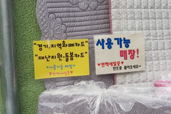 하남시 덕풍시장 내 한 이불가게가 재난기본소득 사용 가능하다는 게시물을 붙여놓고 손님 방문을 유도하고 있다. (사진=장민호 기자)