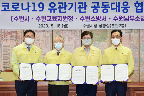 18일 오전 수원시청 상황실에서 코로나19 유관기관 공동대응 협약식에 참석한 기관장들이 협약서를 들고 기념촬영을 하고 있다. 왼쪽부터 이정래 수원남부소방서장, 이형우 수원교육장, 염태영 수원시장, 임정호 수원소방서장. (사진제공=수원시청)
