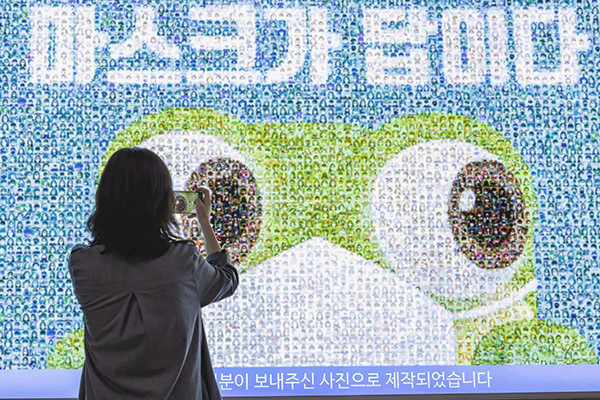 수원시가 시민참여형으로 제작한 ‘마스크가 답이다’ 광고물을 시민이 사진으로 찍고 있다. (사진제공=수원시청)