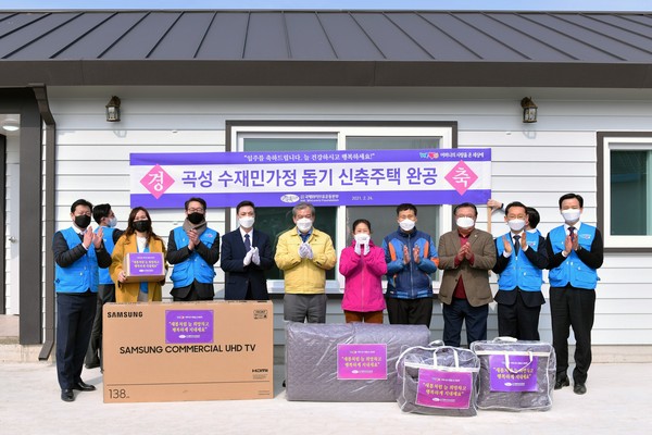 새 보금자리를 얻은 수혜가정 부부와 유근기 곡성군수, 정인균 곡성군의회 의장, 위러브유 회원들이 입주를 축하하며 밝게 웃고 있다.