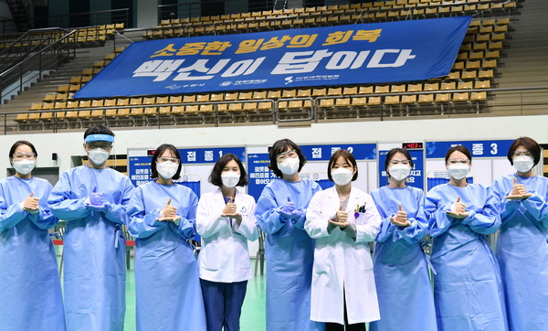 수원시 제1호 예방접종센터인 아주대학교 체육관에서 접종을 담당하는 의료진들이 ‘덕분에’ 챌린지 수어를 하며 기념 촬영을 하고 있다. (사진제공=수원시청)