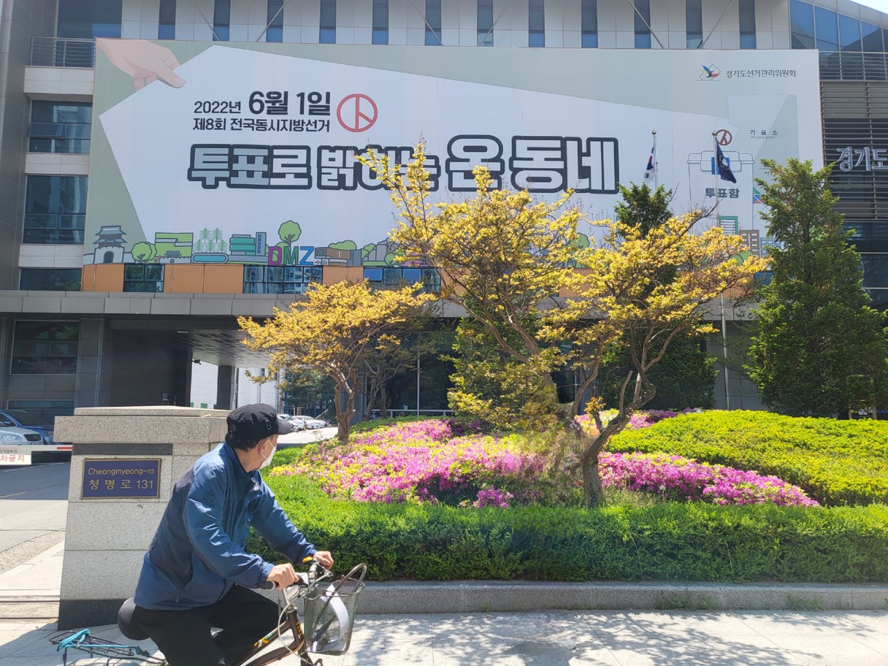 3일 오후 경기도선거관리위원회 벽에 설치된 현수막을 한 시민이 자전거를 타고 지나가며 바라보고 있다. (사진=김유정 기자)