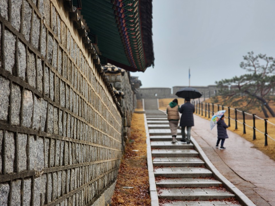 비가 내리는 수원화성 창룡문 성곽을 한 가족이 걷고 있다. ​​​​​​​16일 목요일인 오늘 경기·인천지역은 대체로 흐리고, 낮까지 비 또는 눈이 조금 내리겠다. (사진=권영복 기자)