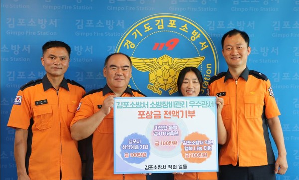 김포소방서 직원들이 포상금 기부를 기념하는 사진을 촬영하고 있다.(사진제공=김포소방서)