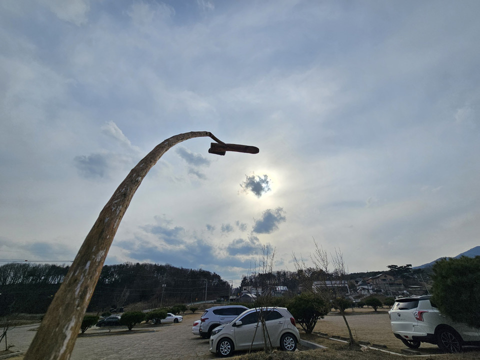 흐린 날씨를 보인 12일 오후 이천시 백사면 도립리 산수유마을 산수유사랑채 인근에 세워진 솟대가 기울어진 채로 구름을 잠시 뚫고 나온 해와 짧은 인사를 나누고 있다. (사진=김광섭 기자)
