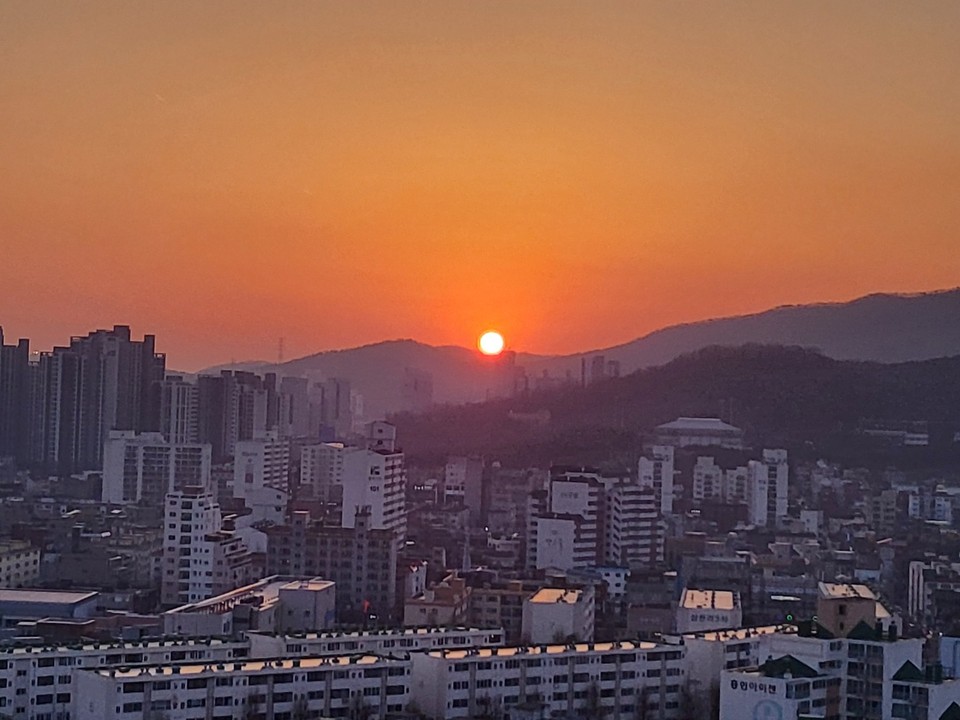 14일 오후 6시27분께 인천시 계양구에서 바라본 빨간 해가 도심 속 사이 멀리 있는 산봉우리 위로 넘어가고 있다. (사진=이복수 기자)