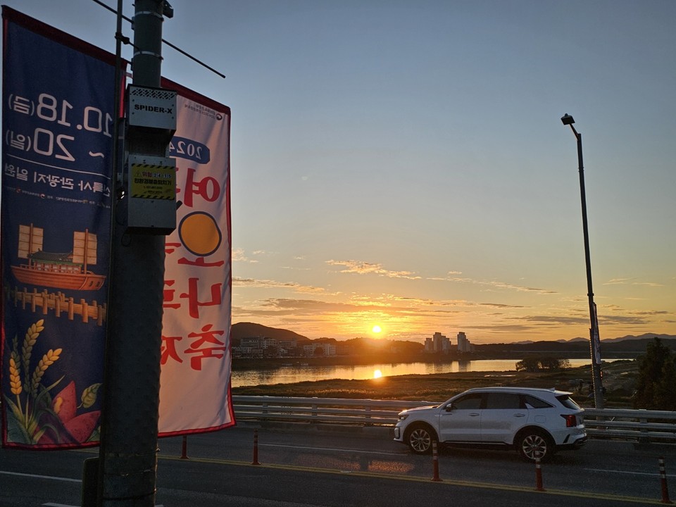 24일 오후 6시10분께 여주대교에서 바라본 남한강 노을이 여주오곡나루축제 배너를 비추고 있다. (사진=김광섭 기자)
