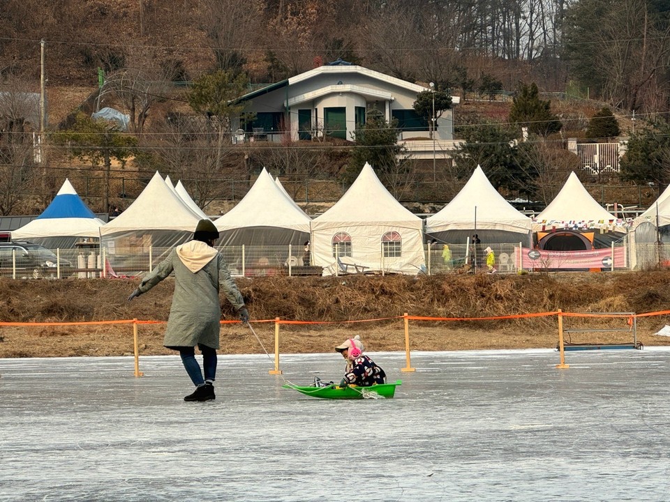 13일 오후 1시30분께 안성시 죽산면 동막골빙어축제장에 마련된 썰매장에서 한 꼬마가 엄마가 끌어주는 얼음썰매에 즐거운 시간을 보내고 있다. (사진제공=김종대 기자)