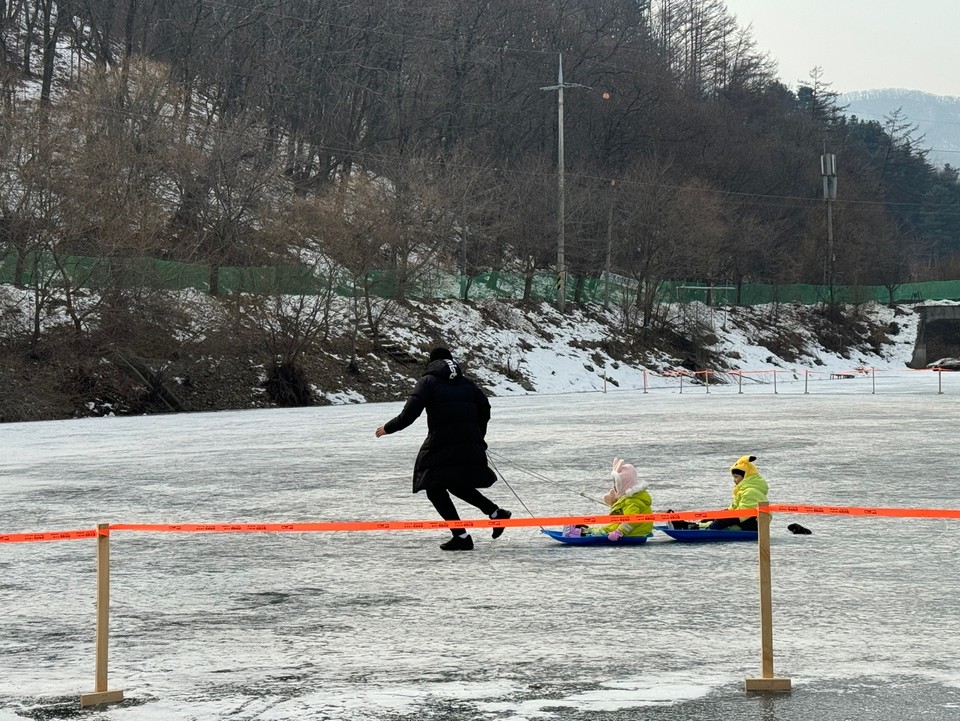 13일 오후 1시30분께 안성시 죽산면 동막골빙어축제장에 마련된 얼음 썰매장에서 쌍둥이로 보이는 아이들을 태운 아빠가 힘차게 썰매를 끌며 즐거운 시간을 보내고 있다. (사진=김종대 기자)