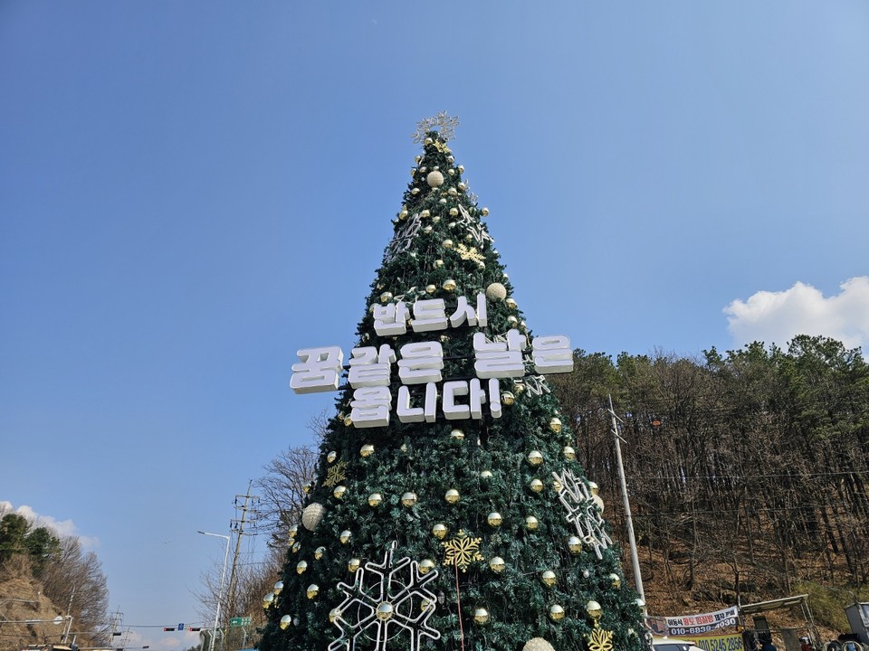 3일 오후 양평을 지나는 출장길에 도로 옆에서 우연히 마주친 풍경 하나가 내 발길을 멈추게 했다. 계절은 분명 봄인데, 한겨울 크리스마스트리 하나가 푸른 하늘을 배경으로 우뚝 솟아 있었다. 트리에 적힌 글귀는 단 한 줄 '반드시 꿈같은 날은 옵니다'였다. (사진=김광섭 기자)