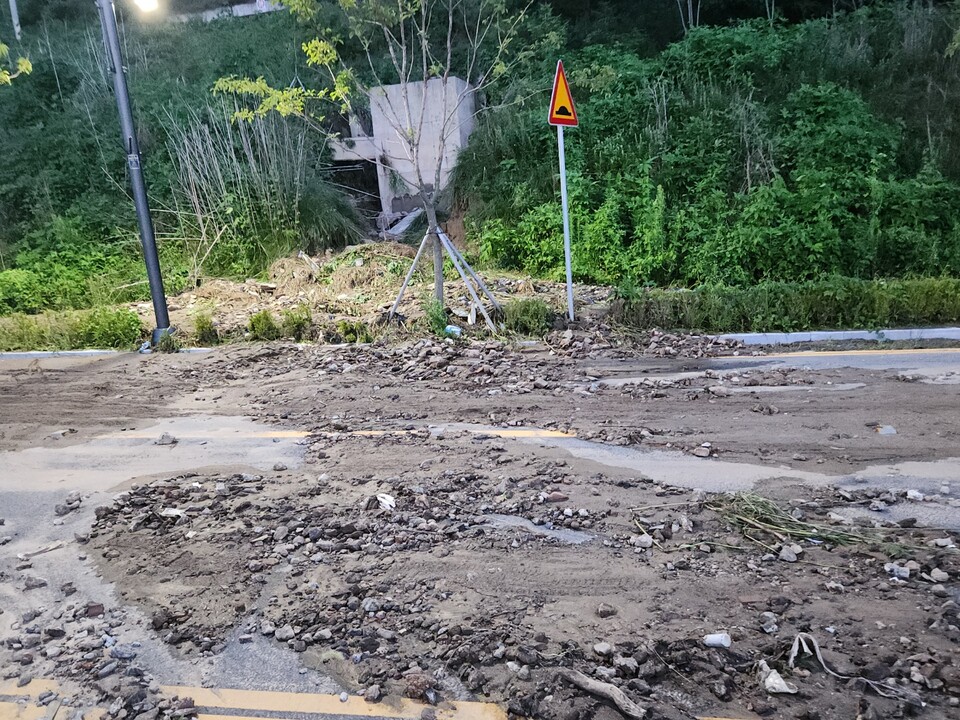 21일 오전 10시20분께 구리~포천고속도로 의정부시 산곡동 130-5 일대 수로에서 범람한 토사가 인근 도로로 유출돼 진흙탕길로 변해 있다. (사진=강상준 기자)