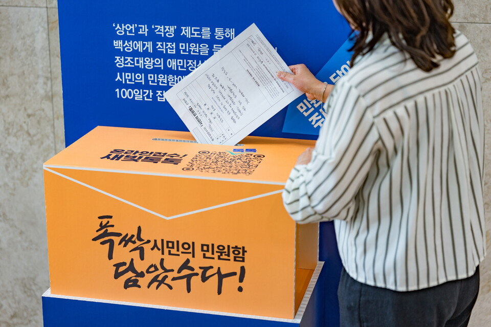 한 시민이 ‘폭싹 담았수다! 시민의 민원함 신청서’를 작성한 뒤 수원시청에 설치된 민원함에 넣고 있다. (사진제공=수원시)
