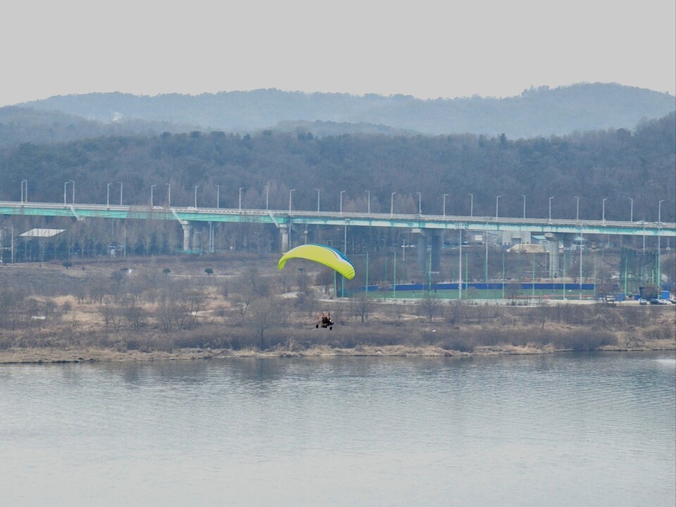 18일 오후 4시29분께 한 동력 페러글라이더가 잔뜩 흐린 여주 남한강 상공을 가로지르며 비행하고 있다. (사진=김광섭 기자)